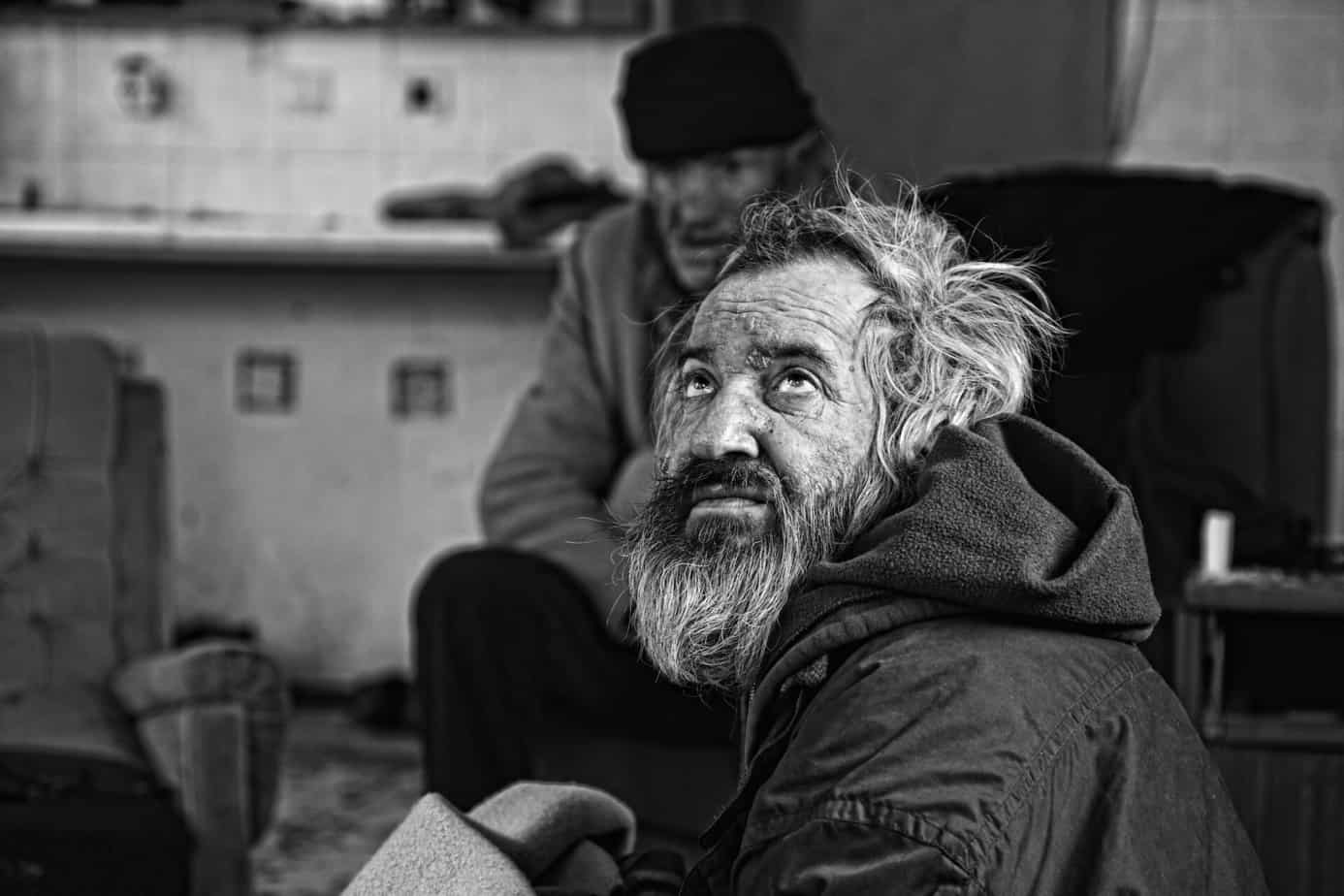 Poor homeless man sitting in abandoned house